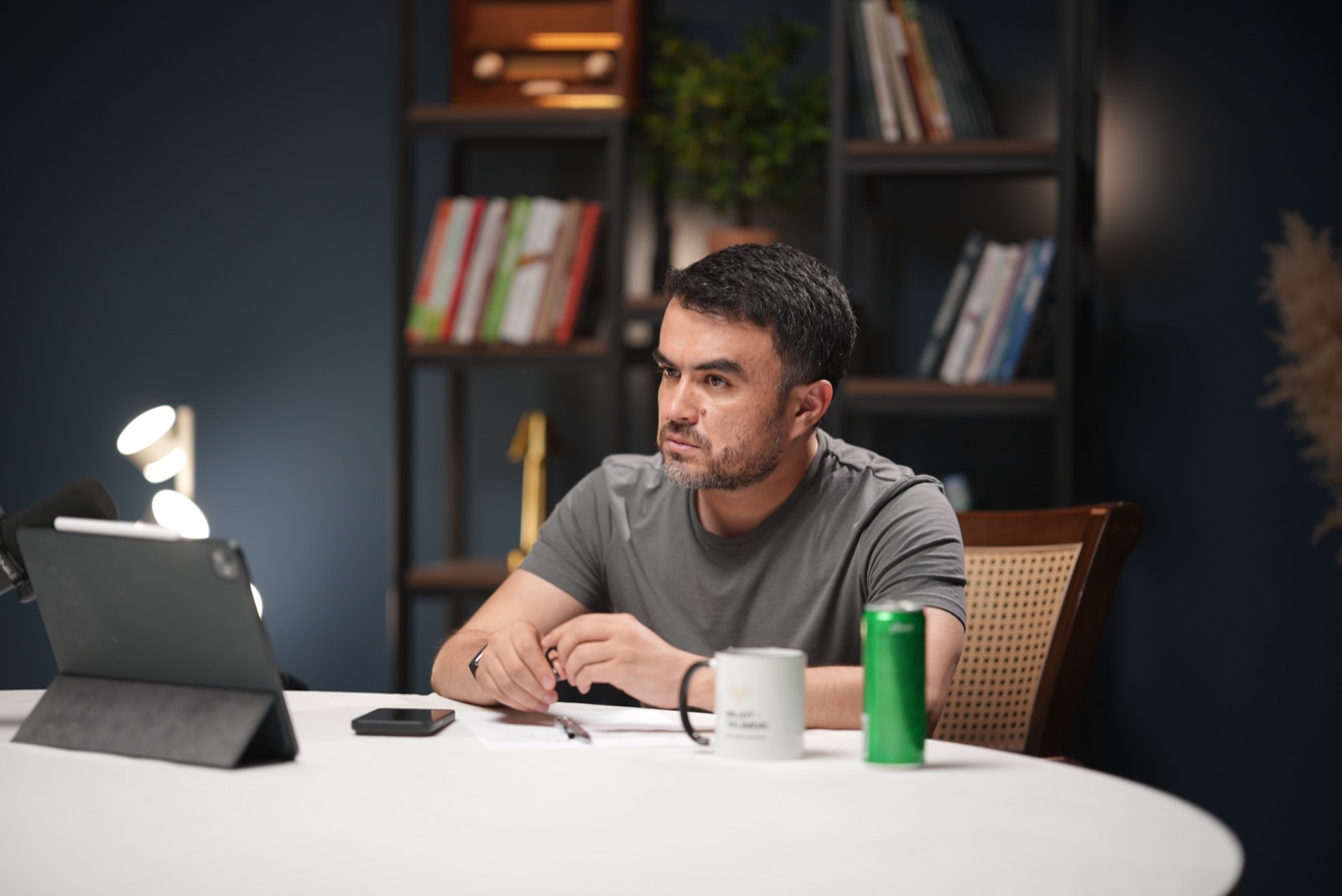 Khurshid Marazikov at his desk in a book-lined study, reviewing work on a tablet.